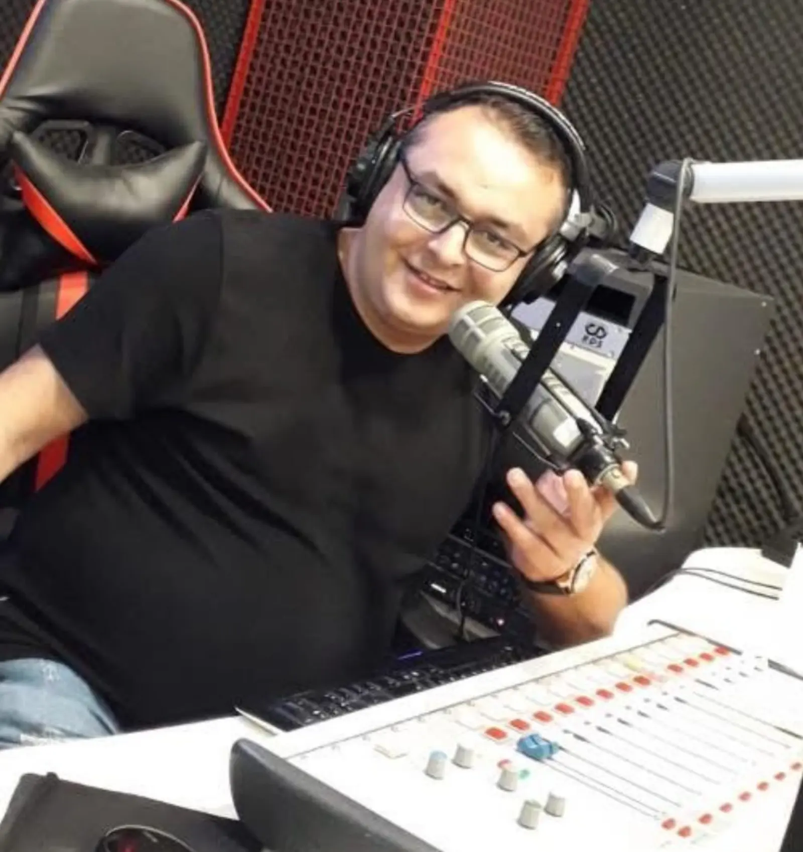 Kulaklıkla mikser başında, mikrofonu tutup gülüyor